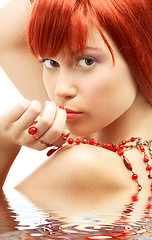 Image showing redhead with red beads looking over shoulder in water