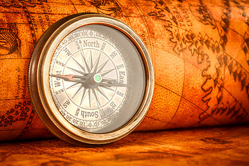 Image showing Vintage compass lies on an ancient world map.