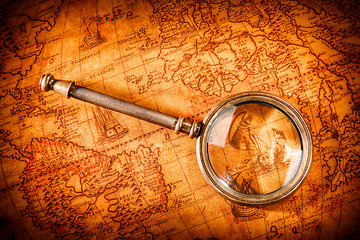 Image showing Vintage magnifying glass lies on an ancient world map