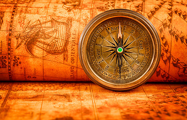 Image showing Vintage compass lies on an ancient world map.