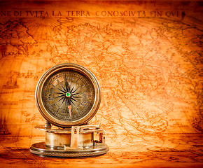 Image showing Vintage compass lies on an ancient world map.