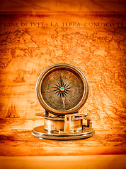 Image showing Vintage compass lies on an ancient world map.