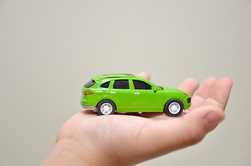 Image showing Green toy car on a right hand