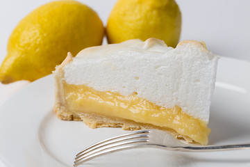 Image showing Lemon meringe pie slice with fork and lemons
