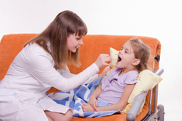 Image showing The doctor looks at the throat of a sick child