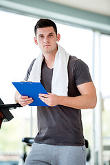 Image showing trainer with clipboard standing in a bright gym