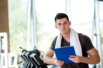 Image showing trainer with clipboard standing in a bright gym