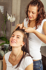 Image showing beautiful young woman makes the hairstyle of his girlfriend at h