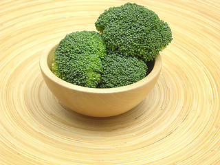 Image showing Wooden bowl with broccoli on bamboo plate