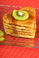 Image showing Stack of heart-shaped pancakes with syrup and kiwi fruit