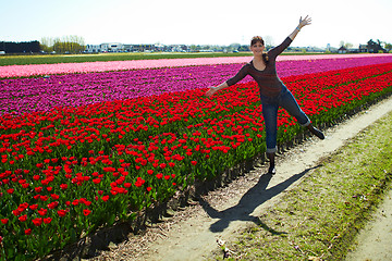 Image showing beautiful young woman having fun on the meadow with red and yellow  flowers tulips, outdoors