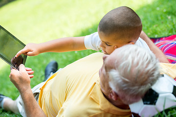 Image showing grandfather and child in park using tablet