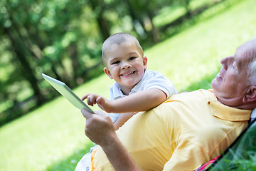 Image showing grandfather and child in park using tablet