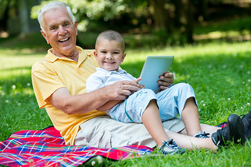 Image showing grandfather and child in park using tablet