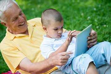 Image showing grandfather and child in park using tablet