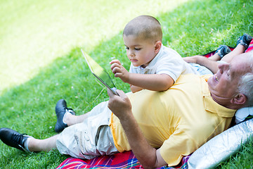 Image showing grandfather and child in park using tablet