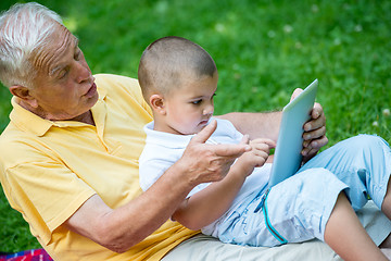 Image showing grandfather and child in park using tablet