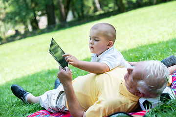 Image showing grandfather and child in park using tablet