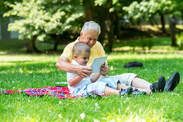 Image showing grandfather and child in park using tablet