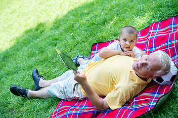 Image showing grandfather and child in park using tablet