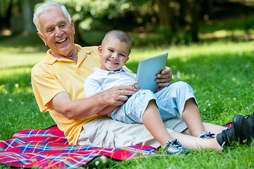 Image showing grandfather and child in park using tablet