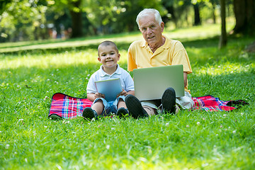 Image showing grandfather and child in park using tablet