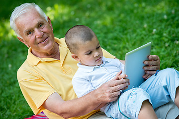 Image showing grandfather and child in park using tablet