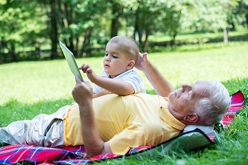 Image showing grandfather and child in park using tablet