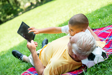 Image showing grandfather and child in park using tablet