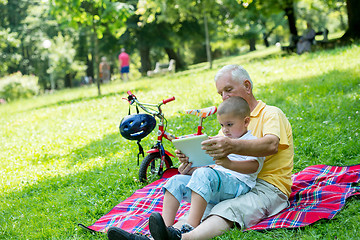 Image showing grandfather and child in park using tablet