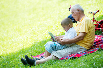 Image showing grandfather and child in park using tablet