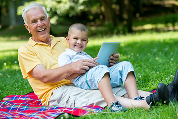 Image showing grandfather and child in park using tablet