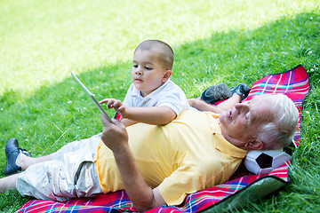 Image showing grandfather and child in park using tablet