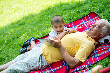 Image showing grandfather and child in park using tablet