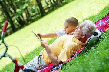 Image showing grandfather and child in park using tablet