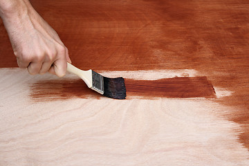 Image showing Man's hand painting a wooden surface