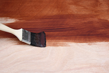 Image showing Paint brush painting a wooden surface