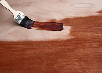 Image showing Painting a wooden surface with a brush