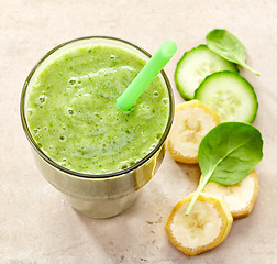 Image showing glass of banana, spinach and cucumber smoothie with a straw