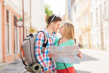 Image showing smiling couple with map and backpack in city