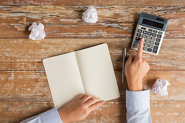 Image showing close up of hands with calculator and notebook