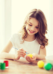 Image showing smiling little girl coloring eggs for easter