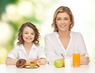 Image showing happy mother and daughter eating breakfast