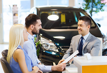 Image showing happy couple with car dealer in auto show or salon