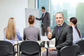 Image showing businessman with team showing thumbs up in office