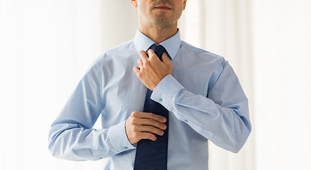 Image showing close up of man in shirt adjusting tie on neck