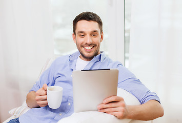 Image showing smiling man with tablet pc and cup at home