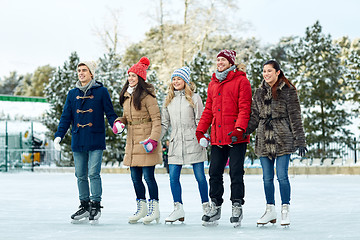 Image showing happy friends ice skating on rink outdoors