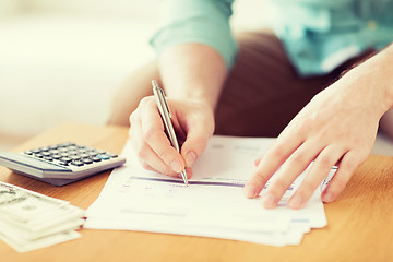 Image showing close up of man counting money and making notes