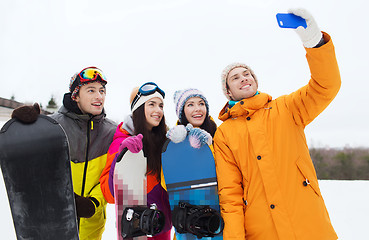 Image showing happy friends with snowboards and smartphone